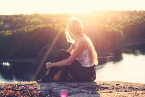 young-woman-in-hippie-style-sitting-on-riverbank-and-looking-at-view