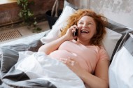 78656323 - mother-to-be talking on phone in bed and laughing
