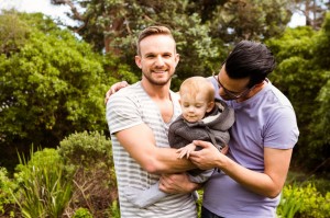 52102075 - smiling gay couple with child in garden