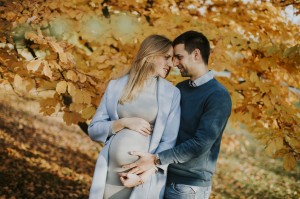 Pregnant woman and her loving man posing at autumn park